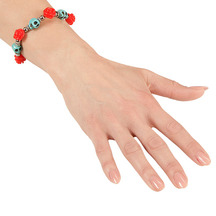 Armband met schedels en rozen om de arm gedragen, rode roosjes en blauwe schedelkralen zichtbaar
