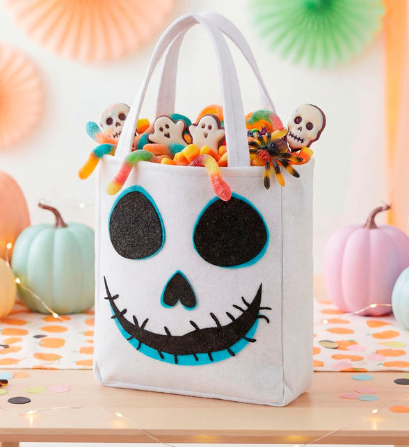 Trick-or-treat tas spook rechtopstaand op tafel tussen pompoenen, gevuld met snoep
