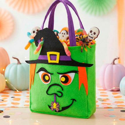 Trick-or-treat tas heksen met snoep tussen pompoenen op een Halloweentafel
