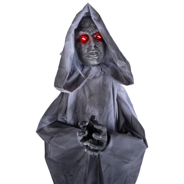 Biddend vrouwenbeeld animatronic van dichtbij met rode ledogen en grijze haarslierten, voor Halloween