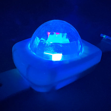 Blauw oplichtende koepel van de lichtgevende armband, zijaanzicht in het donker