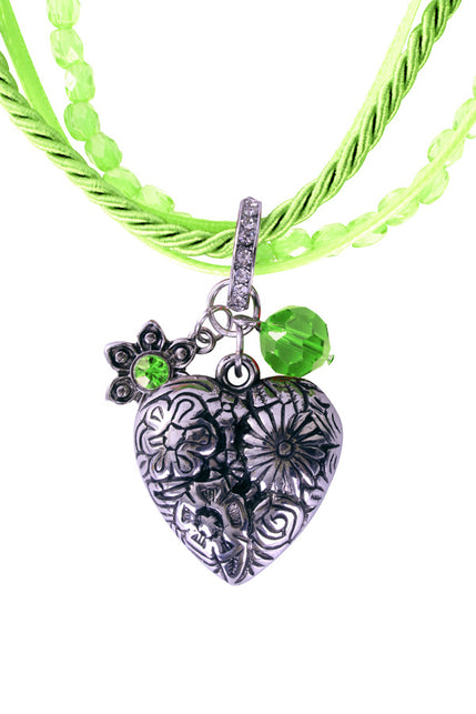 Detail van de hartbedel met bloemenreliëf, bloemetje en groene facetsteen aan de groene tirolerketting