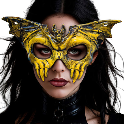 Geel vleermuisschedelmasker op gezicht van vrouw met vleugels langs de slapen en tanden op de wangen