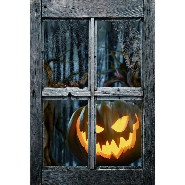 Griezelige raamdeco met oplichtende pompoenkop en spinnenwebben achter een verweerd grijs kozijn voor Halloween