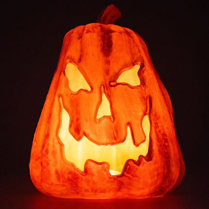 Grijnzende pompoen met vlammend lichteffect, oranje oplichtend grijnsgezicht in het donker met Halloween