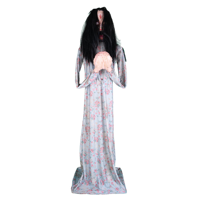 Halloween animatronic Beatrice met nephersenen in beide handen, opgericht in bloemetjesjurk