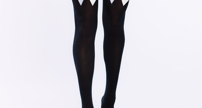 Kniekousen zwart met witte strik gedragen boven de knie bij een korte zwarte rok, dames beenmode