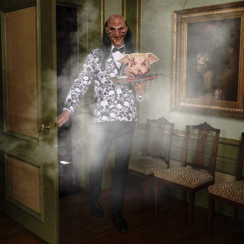 Latex butlermasker met één tand, gedragen in een mistige hal op Halloween