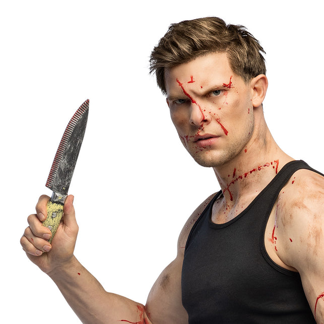 Mes Grimblade met zilvergrijs lemmet en geel heft, rechtop vastgehouden bij een slasherlook voor Halloween