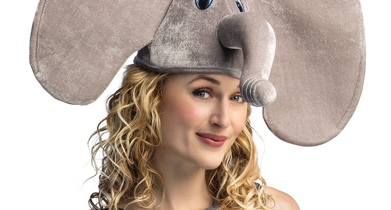Muts olifant in grijs plush met grote flaporen en opstaande slurf, gedragen door een vrouw op carnaval