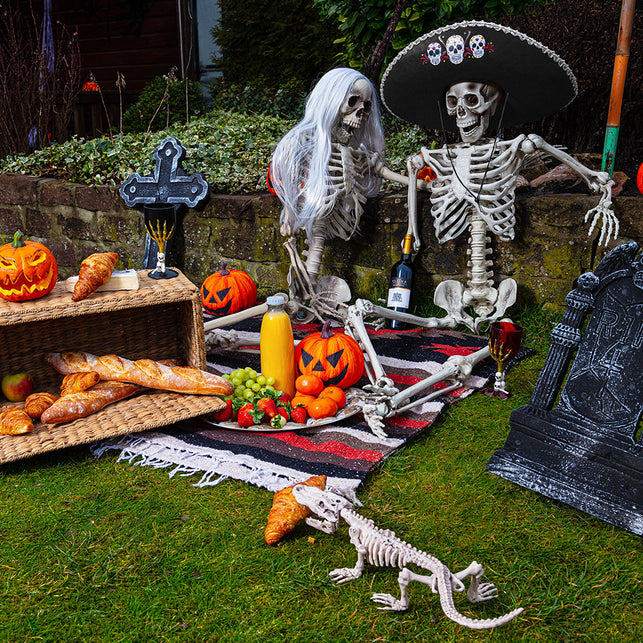 Plastic kelk Skull claw zwart met rode drank tussen pompoenen, skeletten en een grafsteen voor Halloween