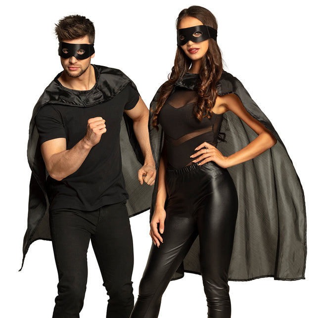 Superheld cape en masker set zwart gedragen door man en vrouw op een verkleedfeest
