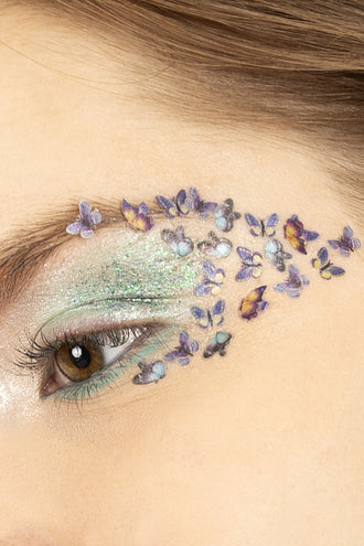 Vlinderglitters in wax op het ooglid, paarse en gele vlindertjes uitlopend naar de slaap voor een themafeest
