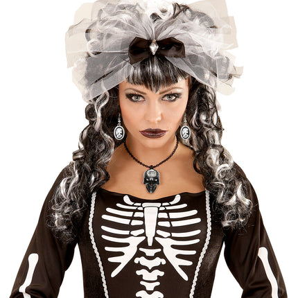 Zilverkleurige camee-oorbellen met skeletdame naast zwart-witte krullen bij skeletjurk