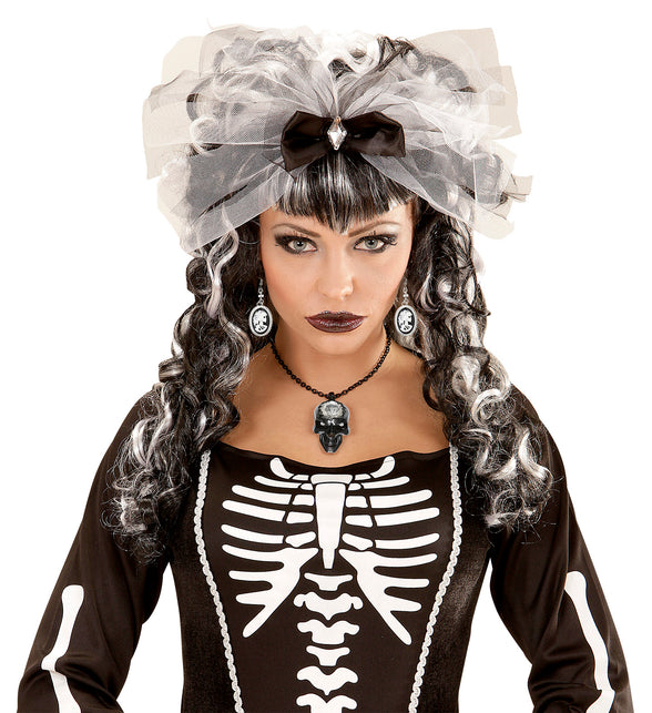 Zilverkleurige camee-oorbellen met skeletdame naast zwart-witte krullen bij skeletjurk